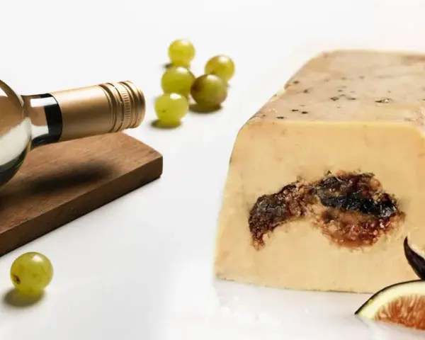 Une bouteille de vin blanc, des raisins et des figues accompagnent ce foie gras. La question est : que boire avec du foie gras ?