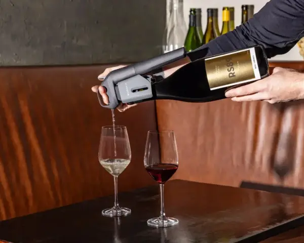 Un appareil verse du vin rouge dans un verre, à côté d'un verre de vin blanc. Parfait pour choisir entre vin rouge, blanc ou rosé.