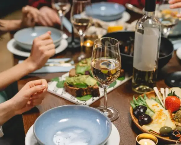 Un dîner convivial avec des amis, des assiettes garnies, des bougies et une bouteille de vin pour cuisiner et accompagner le repas.
