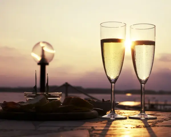 Deux flûtes de le meilleur prosecco scintillent au soleil couchant, accompagnées d'une assiette d'amuse-bouches.