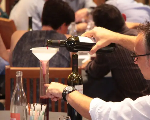 Dégustation de vin rouge, un homme verse du cépage Syrah, d'origine française, dans un verre gradué.