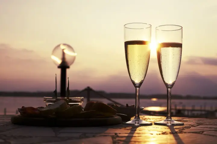 Deux flûtes de le meilleur prosecco scintillent au soleil couchant, accompagnées d'une assiette d'amuse-bouches.