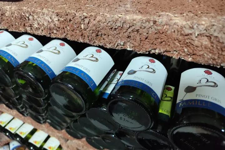Bouteilles de cépage Pinot Gris d'Alsace, étiquetées "Famille Ancel", rangées sur une étagère en briques.