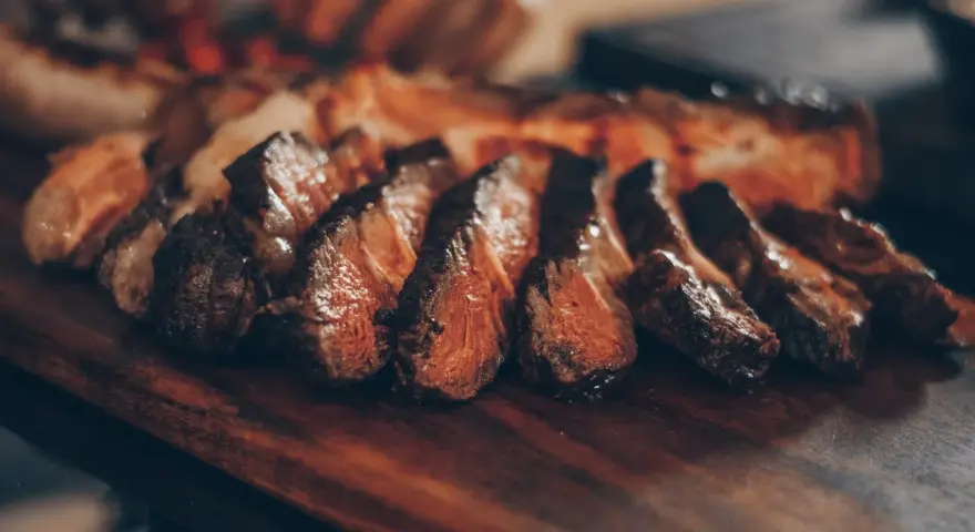 Tranches de viande grillée sur une planche en bois. Idéal pour savoir que boire avec une pierrade viande.