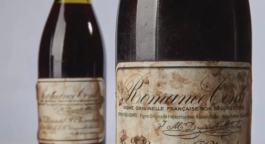Deux bouteilles de vin Romanée-Conti, dont une avec une étiquette ancienne et jaunie.