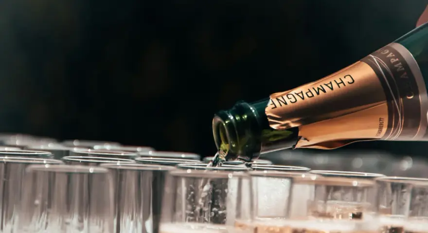 Une bouteille de champagne verse son contenu pétillant dans une rangée de flûtes. Le début d'une célébration avec le meilleur champagne du monde.