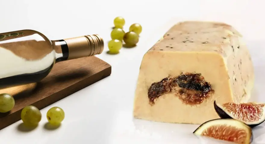 Une bouteille de vin blanc, des raisins et des figues accompagnent ce foie gras. La question est : que boire avec du foie gras ?