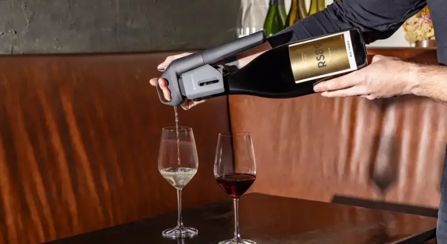 Un appareil verse du vin rouge dans un verre, à côté d'un verre de vin blanc. Parfait pour choisir entre vin rouge, blanc ou rosé.