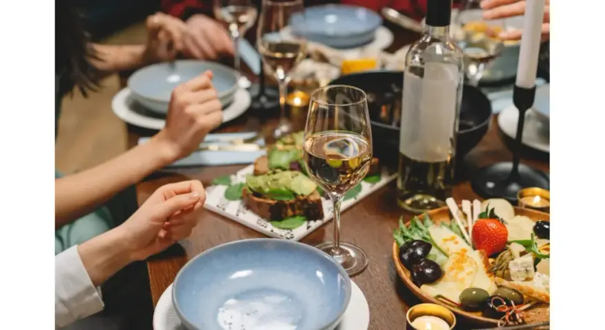 Un dîner convivial avec des amis, des assiettes garnies, des bougies et une bouteille de vin pour cuisiner et accompagner le repas.