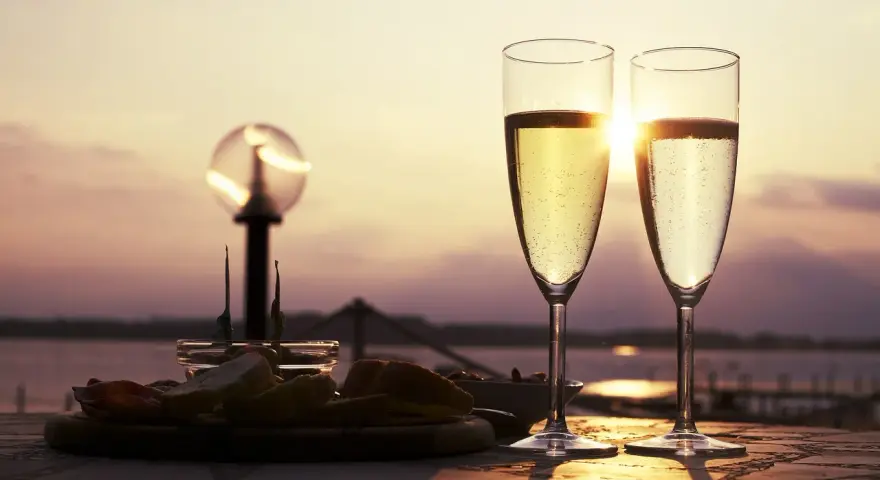 Deux flûtes de le meilleur prosecco scintillent au soleil couchant, accompagnées d'une assiette d'amuse-bouches.