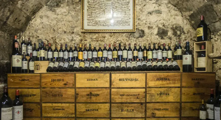 Cave à vin de la côte de Beaune, remplie de bouteilles et de caisses en bois étiquetées avec des noms de villes.
