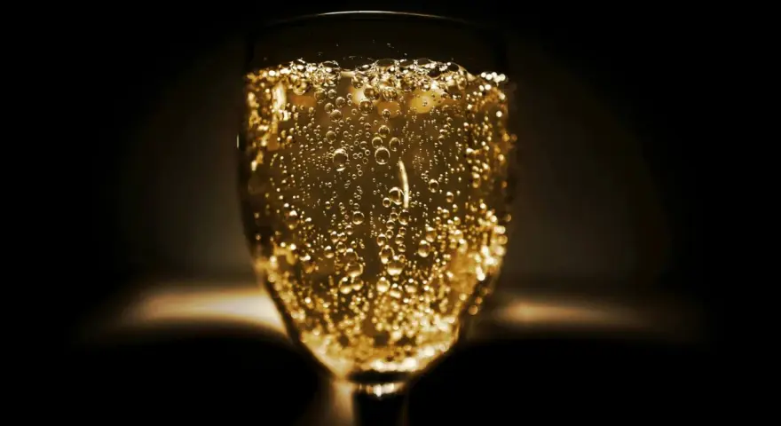 Un verre de vin mousseux scintillant, rempli de bulles dorées, prêt à célébrer.