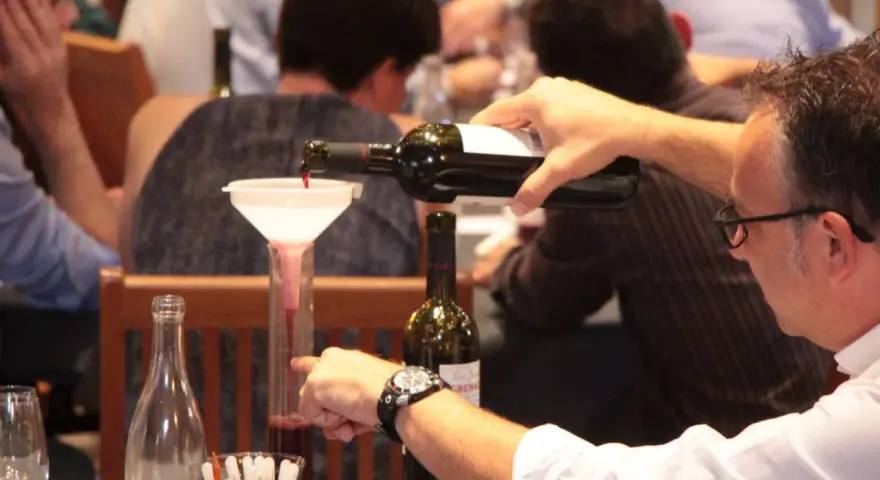 Dégustation de vin rouge, un homme verse du cépage Syrah, d'origine française, dans un verre gradué.