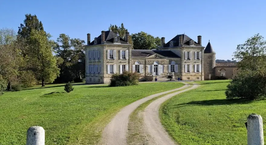Un magnifique chateau la France, avec une allée sinueuse traversant une pelouse verdoyante sous un ciel bleu clair.