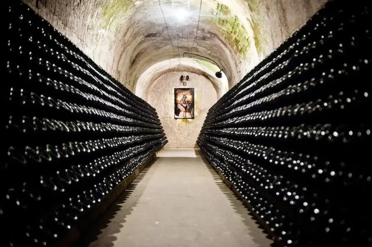 Cave voûtée remplie de bouteilles de champagne, évoquant un avis sur le champagne Canard-Duchêne.