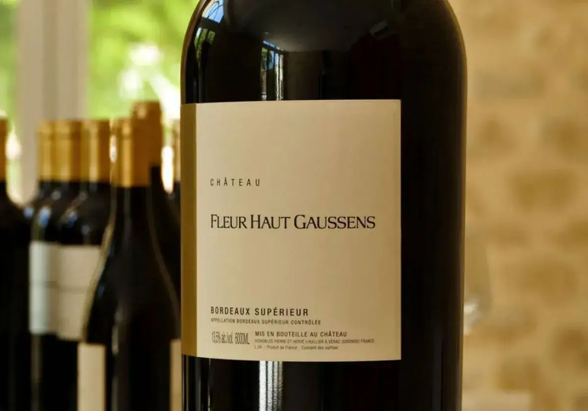 Bouteille de vin rouge Ch&acirc;teau Fleur Haut Gaussens, Bordeaux Sup&eacute;rieur, avec d'autres bouteilles en arri&egrave;re-plan.