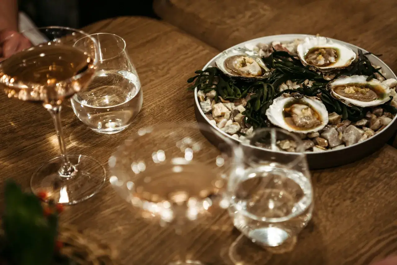 Plateau de fruits de mer frais avec des hu&icirc;tres, accompagn&eacute; de verres de vin. Quel vin avec un plateau de fruits de mer ? Un blanc sec, bien s&ucirc;r !