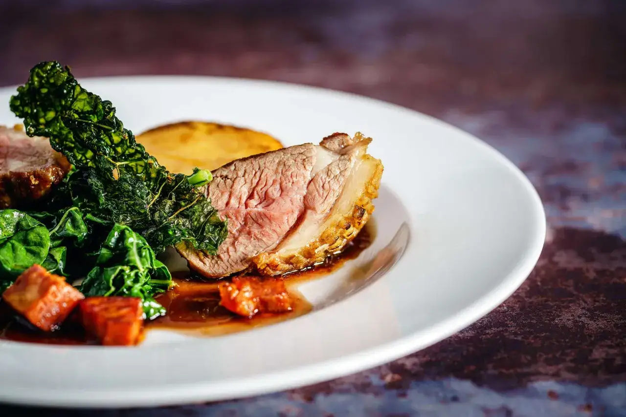 Un plat d'agneau ros&eacute; avec des l&eacute;gumes verts et une tranche de pomme de terre. Quel vin avec agneau ? Un Bordeaux ou un vin de la Vall&eacute;e du Rh&ocirc;ne serait parfait.