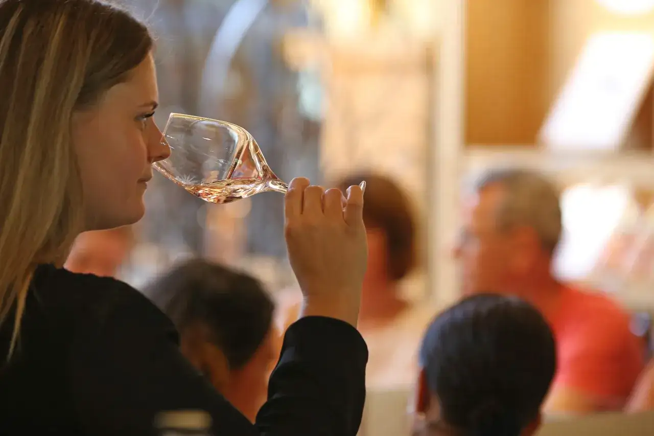 Une femme d&eacute;guste un verre de bon ros&eacute;, le nez dans le verre, lors d'une d&eacute;gustation.