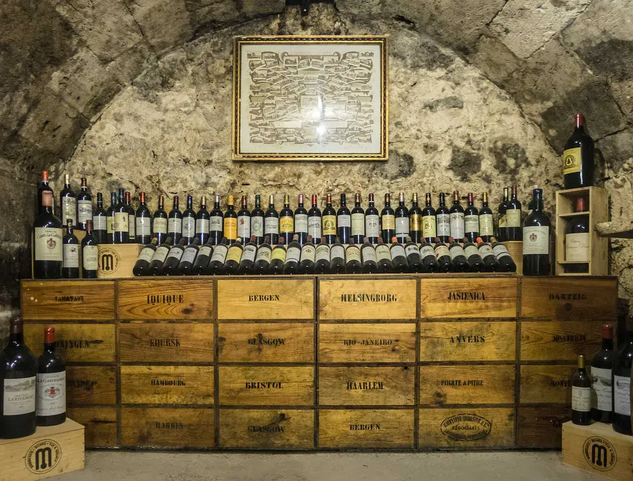 Cave &agrave; vin remplie de bouteilles. Des caisses en bois &eacute;tiquet&eacute;es de noms de villes sugg&egrave;rent un potentiel pour investir dans le vin.