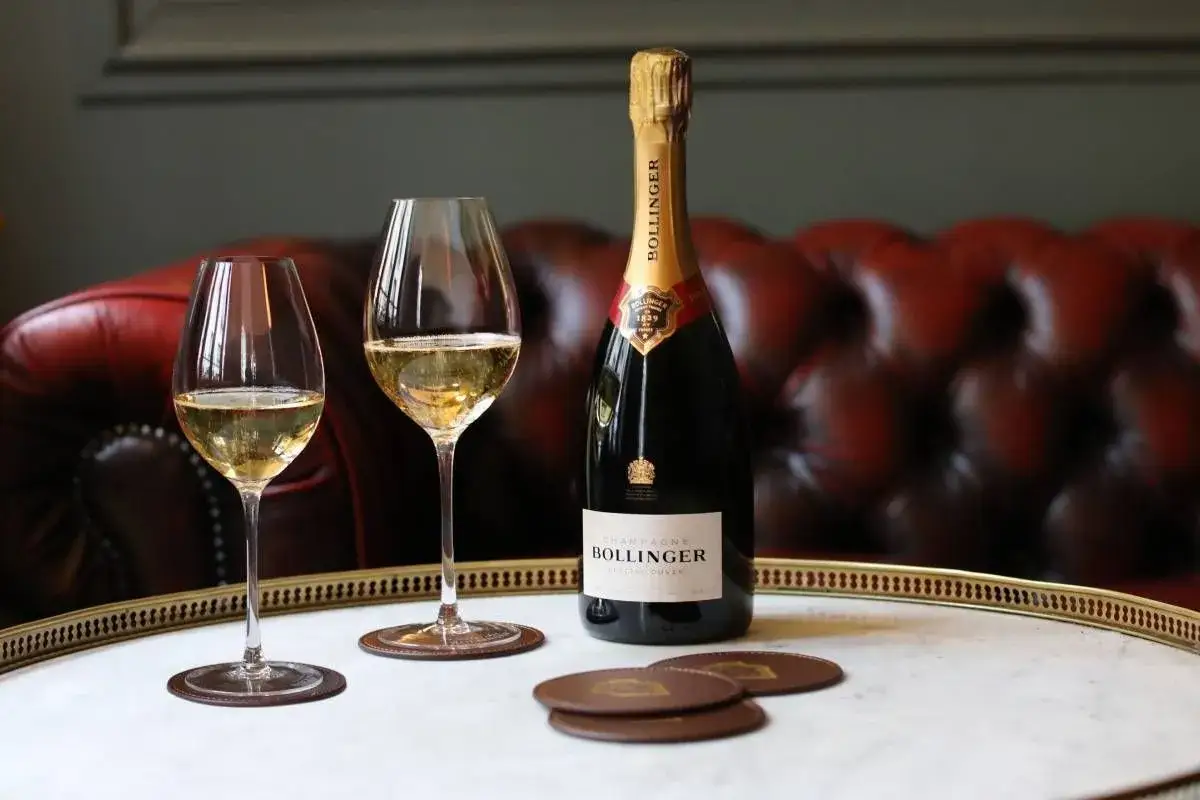 Bouteille de Bollinger et deux verres de champagne sur un plateau, pr&ecirc;ts pour une d&eacute;gustation digne de Charles Armand de Belenet.