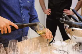 Un homme verse du vin blanc, peut-être un pinot gris, dans un verre. Il sera parfait avec du poisson.
