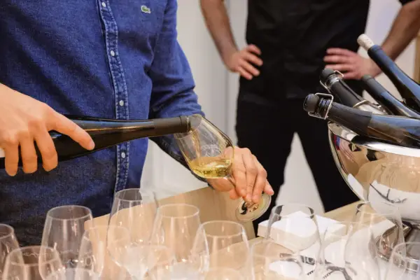 Un homme verse du vin blanc, peut-être un pinot gris, dans un verre. Il sera parfait avec du poisson.