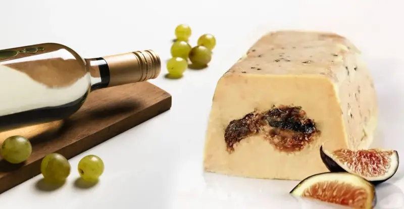 Une bouteille de vin blanc, des raisins et des figues accompagnent ce foie gras. La question est : que boire avec du foie gras ?